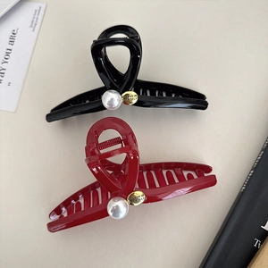 Festive red and black ribbon hair claws with pearls and gold tags on light background