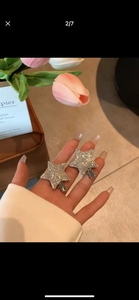 Gros plan de barrettes étoile Y2K scintillantes avec strass blancs tenues à la main