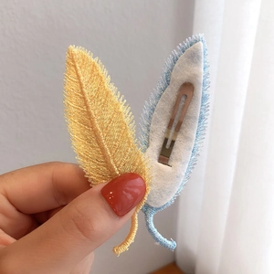 Detail showing embroidered leaf hair clips with delicate stitching and metal spring clips