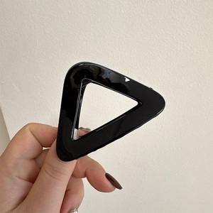 Hand holding a minimalist black triangular hair claw clip with a glossy finish for women