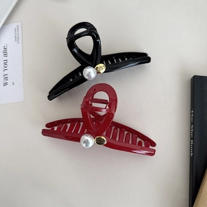 Detail of red and black shark hair clips with large pearls and golden belief charms