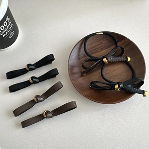 Detail view of premium leather bow hair clips and scrunchies set with metallic accents