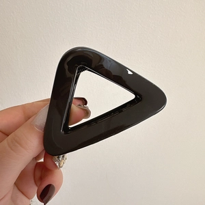 Detailed macro view of the glossy black triangle hair claw clip with its internal spring
