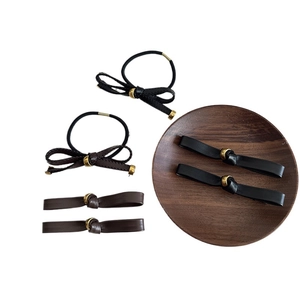 Faux leather bow hair tie and clip set in black and dark brown with golden metal ring detail