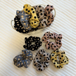 Close-up of colorful polka dot satin scrunchies in a decorative white metal basket