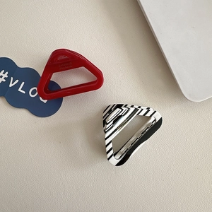 Detailed view of red and black-white triangle acetate claw clips on leather background