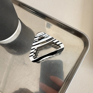 Elegant triangular acetate hair claw with classic black and white horizontal stripes