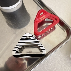 Macro detail of red and striped acetate triangle hair clips on a metal tray