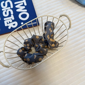 Detailed view of dark blue satin polka dot scrunchie on vintage magazine background
