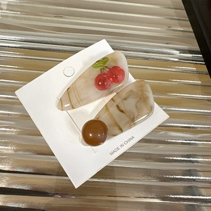 Sweet translucent cherry hair clips set with marble texture on silver display surface