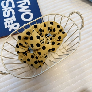 Close-up of yellow satin polka dot scrunchie fabric texture and elastic design