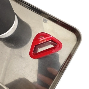 Elegant bright red triangular acetate hair claw clip with golden handmade logo on a tray