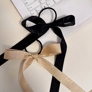 French style bow hair tie set in black and champagne gold satin on a white desk