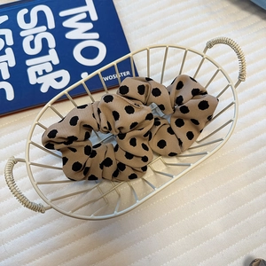 Close-up of khaki satin polka dot scrunchie in a white basket on a vintage book