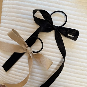 Detail of satin bow hair ties in black and champagne with long flowing ribbons