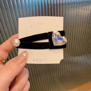 Detail of black velvet hair clip with heart crystal and white pearl on display card