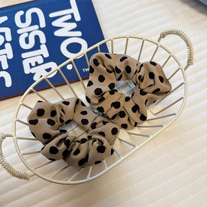 Detail showing two satin polka dot scrunchies with pleated texture in a white metal basket