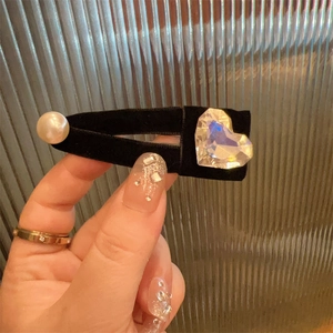 Detail of a black velvet hair clip with a large heart crystal and white pearl ornament