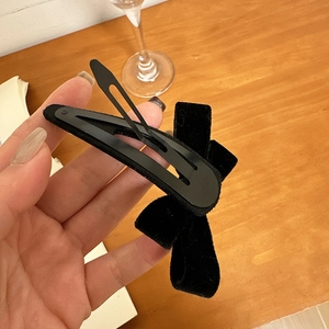 Detailed close-up of a black velvet bow hair clip with a classic metal snap base