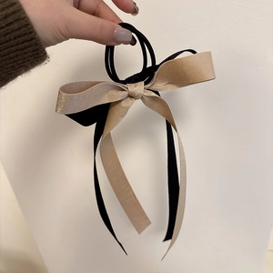 Detail of a black and champagne gold satin double bow hair tie with long ribbons