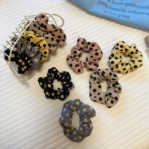 Polka dot satin scrunchies in various colors displayed in a white wire basket