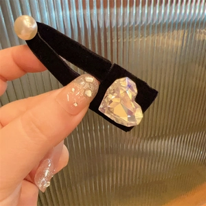 Detail of velvet bow hair clip with heart-shaped crystal and white imitation pearl