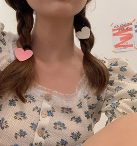 Detail shot of cute matte pink and white heart-shaped hair clips worn by a model