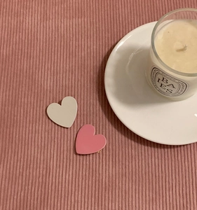 Detail of cream and pink heart-shaped hair clips on a soft textured fabric background