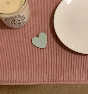 Detailed view of light green resin heart hair clip on pink corduroy fabric background