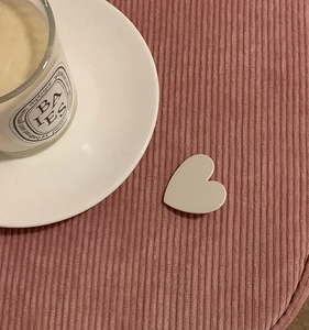 Close-up of a cream heart hair clip placed on a pink corduroy fabric background