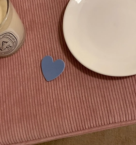 Close-up of matte dusty blue heart hair clip on pink corduroy fabric background