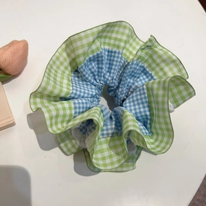 Détail d'un chouchou à carreaux verts avec bordure en dentelle blanche de style vintage