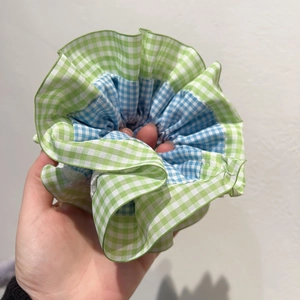 Détail du chouchou à carreaux vichy vert et bleu avec volants superposés et plis denses