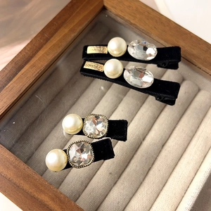 Détail de barrettes en velours noir avec perles, cristaux et plaque en métal doré