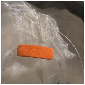 Detail einer hellorangen rechteckigen Haarspange mit strukturierter Strickoberfläche
