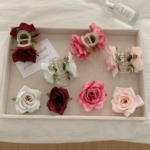 Top view of romantic silk rose hair claw clips and floral accessories on a beige tray