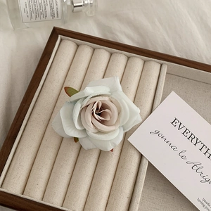 Detailed close-up of a rustic wood jewelry display tray with white faux rose decoration