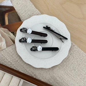 Set di fermagli per capelli con perle e pietre preziose scure su piatto di porcellana bianca