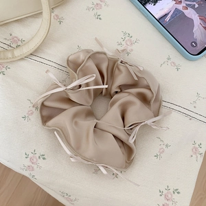 Detail of champagne gold satin scrunchie with silk ribbon bows on floral fabric
