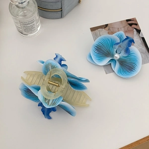 Detailansicht blauer Orchideen-Haarspangen mit Perle auf minimalistischem Hintergrund