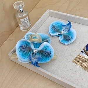 Nahaufnahme von blauen Orchideen-Haarklammern mit Verlaufs-Effekt und Perle im Tablett