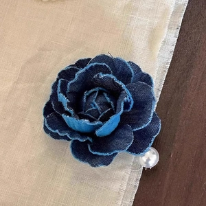 Detailed close-up of a blue denim rose hair clip with a centered white pearl accent