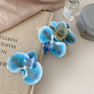 Detailansicht der blauen Orchideen-Haarklammer mit Perlenverzierung und Harzstruktur