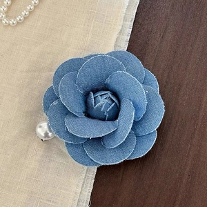 Detailed macro of vintage denim camellia hair clip with delicate pearl accent and frayed edges