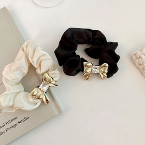 Close-up of cream and black satin scrunchies with metal bow and crystal accents