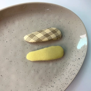 Close-up of yellow plaid and solid candy-colored hair clips set on a beige ceramic plate