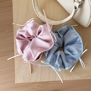 Detailed shot of pink and light blue satin scrunchies with delicate ribbon bows