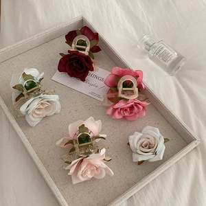 Romantic floral claw clips with realistic fabric roses in assorted colors on a linen tray