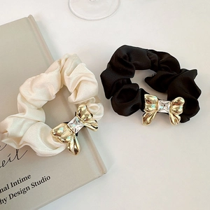 Detail of silk hair scrunchies with golden metal bow and sparkling square crystal