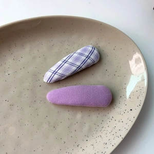 Close-up of lavender and purple plaid fabric BB hair clips on a ceramic plate